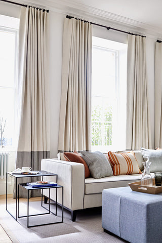 Lounge room with long neutral curtains.