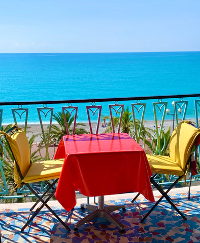 table and chairs on sunny terrace overlooking the sea