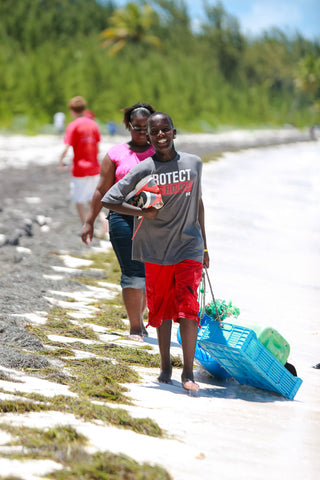 Students collect and remove plastic debris and other trash during a  beach clean-up in the Bahamas