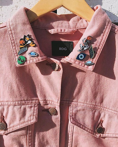 Pink denim jacket with enamel pins on the collar