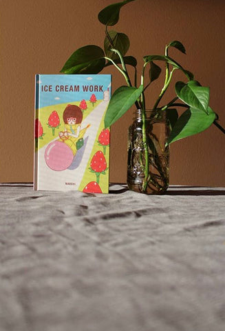 ice cream work sits back in the frame surrounded by green leaves