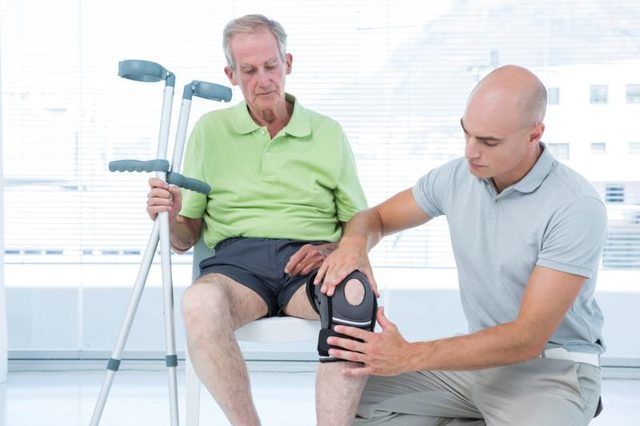 A doctor adjusts a knee immobilizer on a patient.