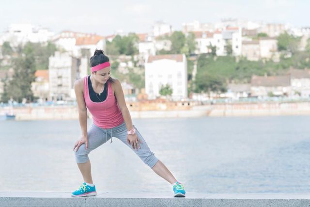 A woman is doing a side lunge, stretching her legs.