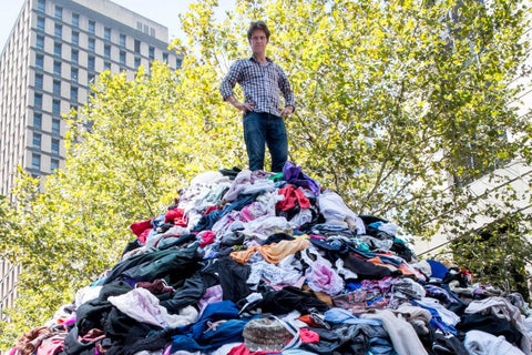 War on Waste Craig Reucassel standing on top of a mountain of clothes in Martin Place