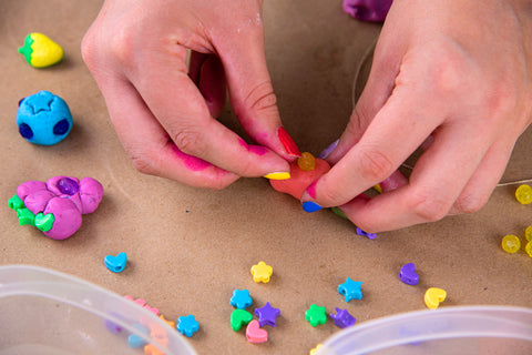 up close hands decorating air dry clay creation with small yellow beads