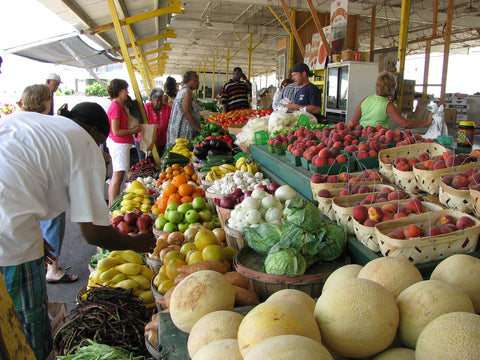 People gathered at a fresh produce stand at a Farmer's Market.