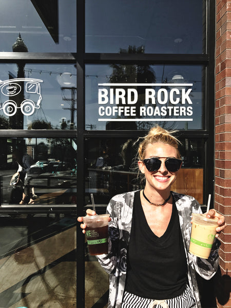 Fashion and lifestyle blogger, and Hiptipico founder Alyssaya poses in front of a coffee shop holding two coffee cups in San Diego, CA