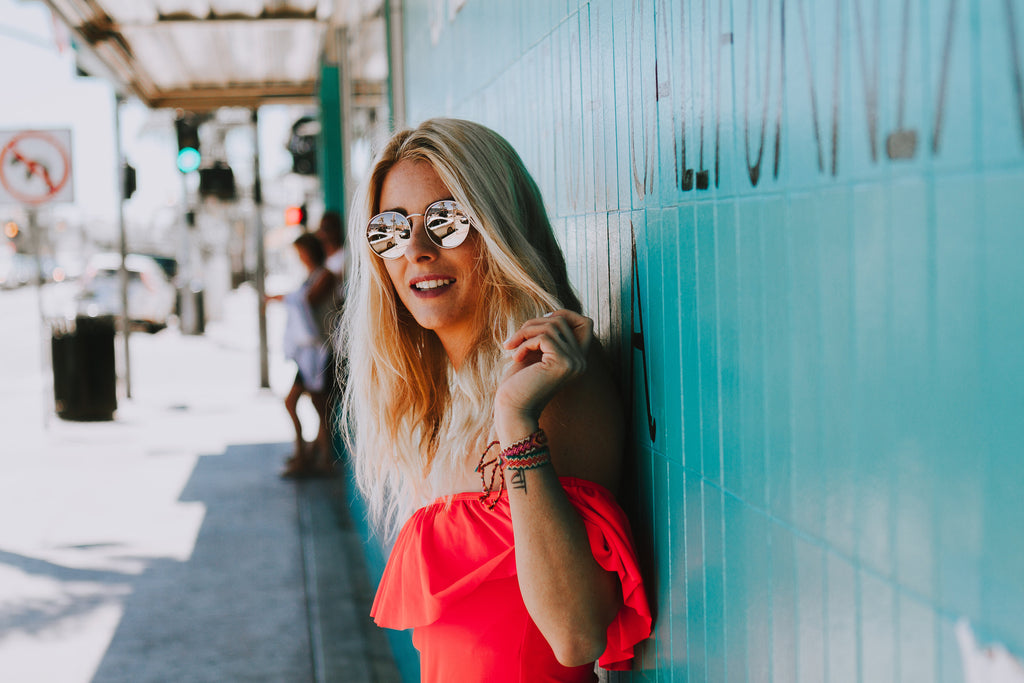 Alyssa wearing a ruffled pink swimsuit in Free People sunglasses and denim cutoffs