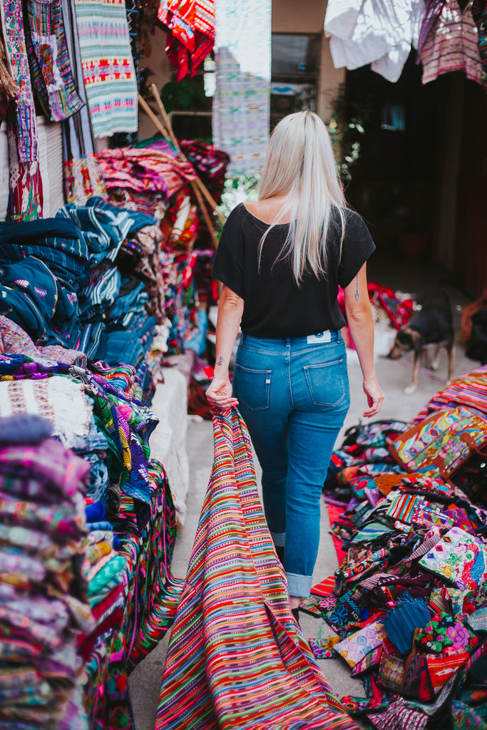 Hiptipico founder Alyssa Yamamoto walks through vibrant Guatemalan market searching for textiles wearing ethically made MUD jeans, ethical fashion bloggers, best ethical fashion options in the US, how to shop for clothes ethically