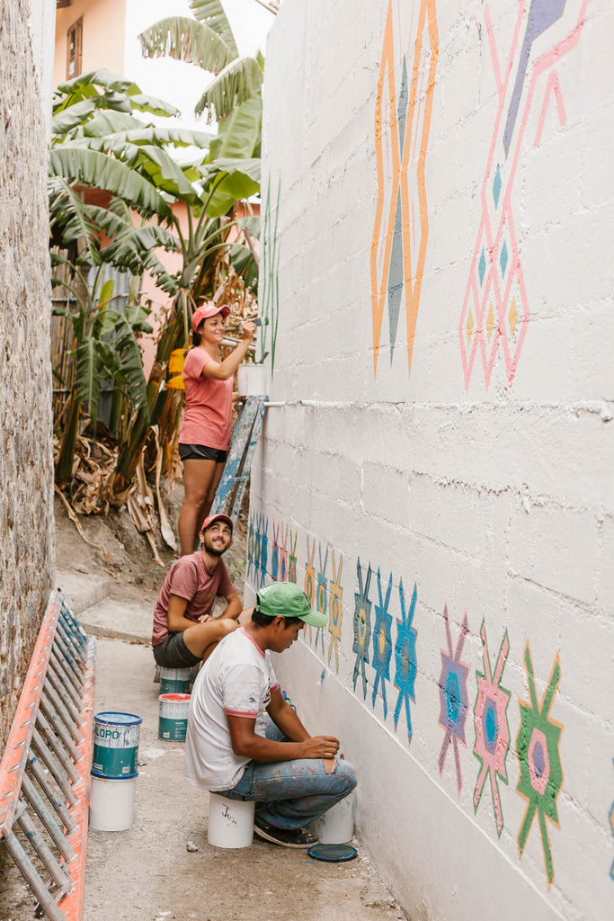 Painters in Santa Catarina alley working as part of the Pintando Santa Catarina Palopó with white wall and traditional designs, ethical travel options, cool things to see on Lake Atitlan, must visit towns Lake Atitlan