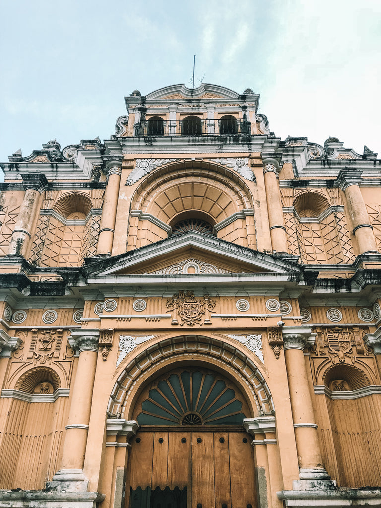 Apricot colonial building in Spanish architecture stands starkly against blue Antigua sky, UNESCO world heritage sites, visit UNESCO sites, see colonial architecture in Guatemala, best architecture to see in Guatemala