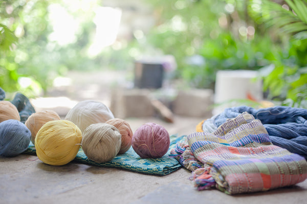 Balls of dyed fabric in assorted colors on top of table runners and textiles on table, authentic naturally dyed products, ethically produced textiles from Guatemala, ethical fashion blogs