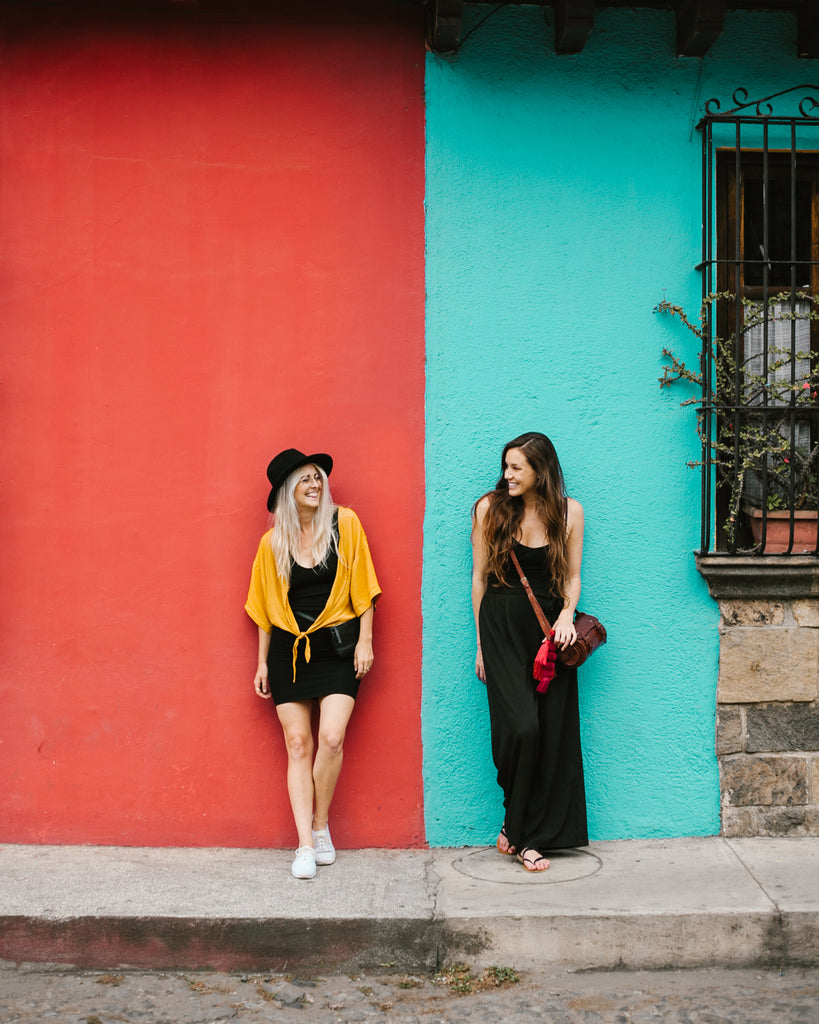 Hiptipico founder Alyssa and She Is Not Lost blogger Carina pose in front of blue and red color blocked building in Antigua Guatemala, Antigua travel, coolest places to see in Guatemala, must visit Guatemala, ethical travel bloggers
