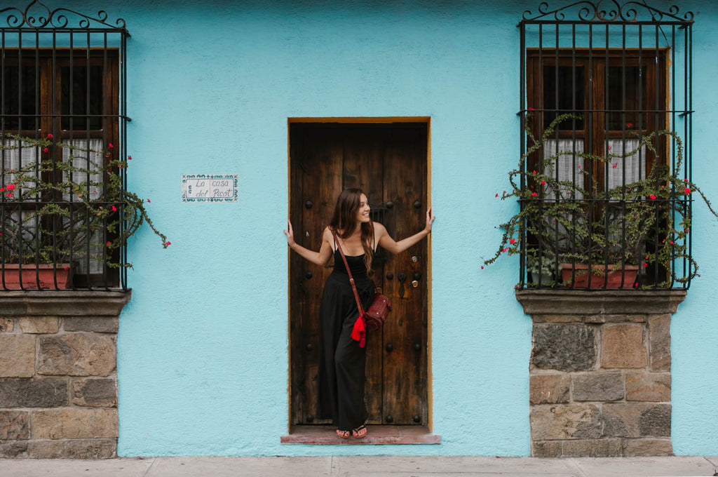 Carina Otero poses in doorway of blue building with red flowers, Antigua Guatemala Travel, Ethical Travel Options in Guatemala, Best Destinations in Antigua