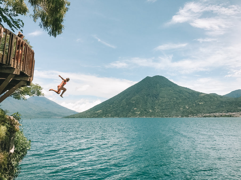 Hiptipico employee in peach suit jumps off sturdy wood platform into Lake AtitlanHiptipico ethical travel, where to go on Lake Atitlan, best swimming spots, cliff jumping Lake Atitlan, diving Lake Atitlan, best diving spots in Lake Atitlan, must do in Guatemala
