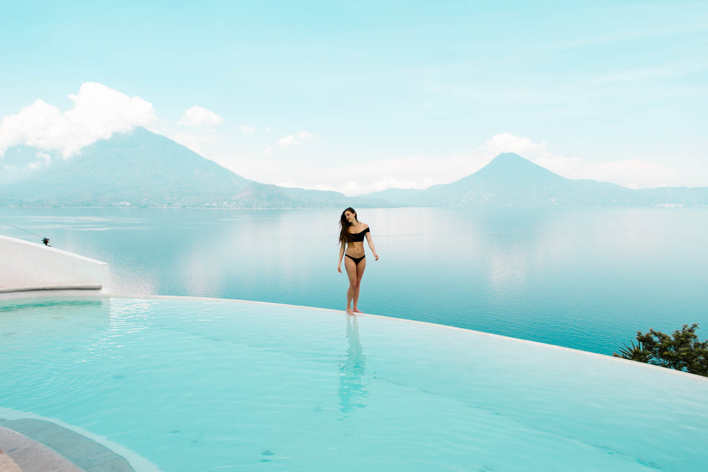 She Is Not Lost blogger Carina Otero poses on edge of infinity pool dropping off to a view of Lake Atitlan, Tzampoc Resort Guatemala, best places to stay in Guatemala, hotels with best views in guatemala, best views of Lake Atitlan, must visit locations guatemala