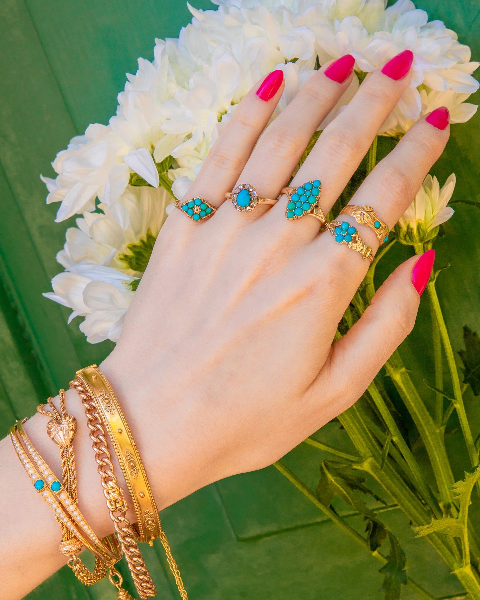 Hand holding Turquoise rings and wearing Gold bracelets