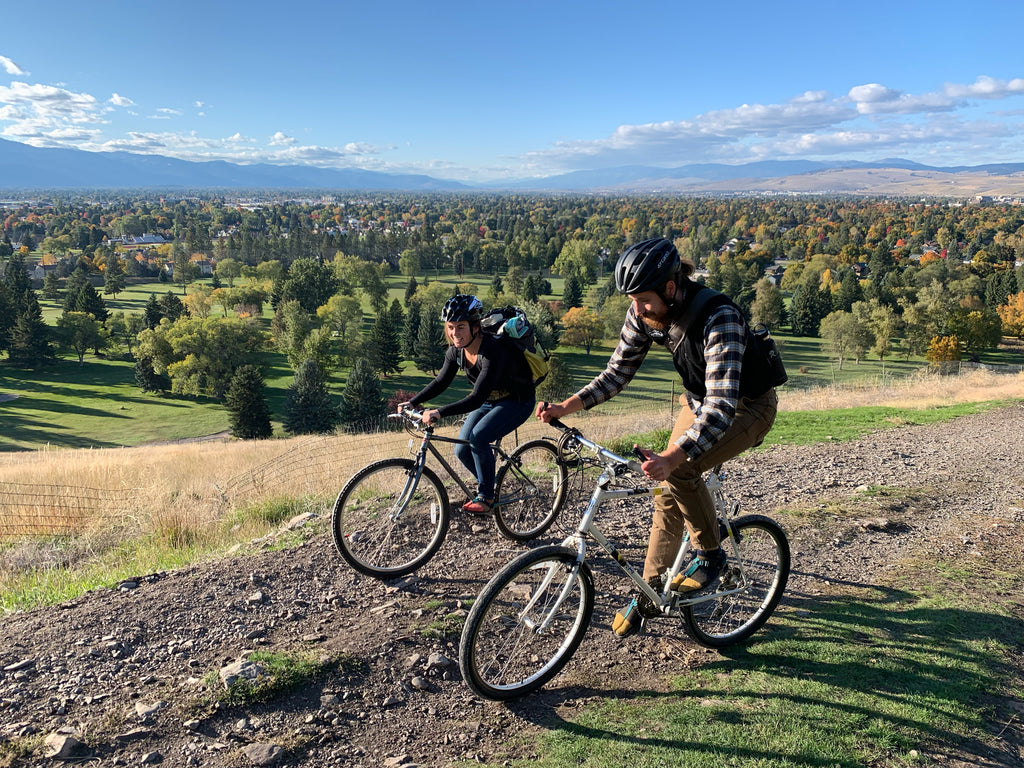 Two people riding bikes while wearing their Bedrock sandals and socks during the fall time in Missoula, Montana