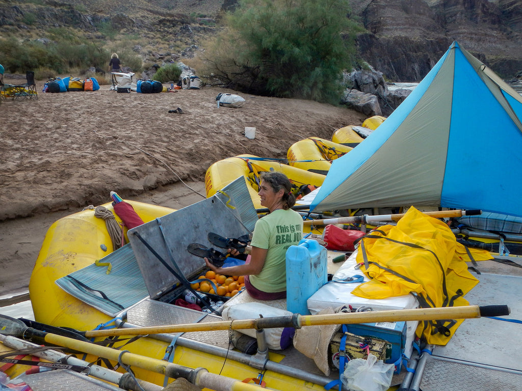 A river guide holding unpacking sandals from their dry storage