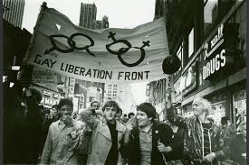 Marches by the GAY LIBERATION MOVEMENT. Group of men and women holding flag with male male, female and female symbols.