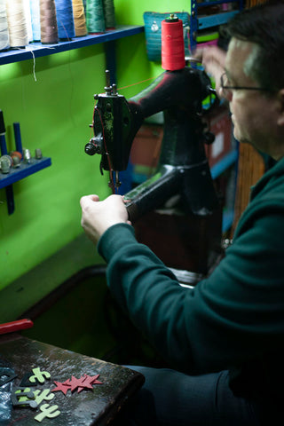 Jose working at his old Singer machine stitching Khu Khu leather pendants 