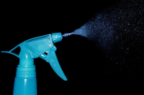 A spray bottle spraying water.