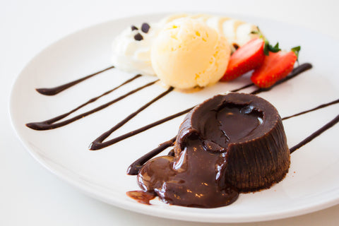 Small chocolate cake with chocolate sauce on white plate