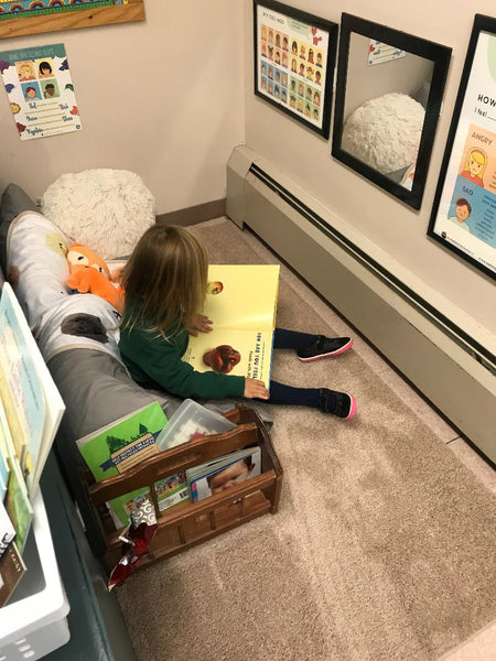 Young child reading a book in a Calming Corner