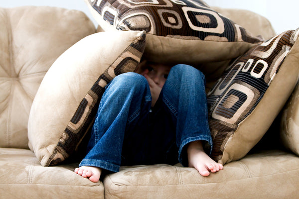 Child hiding under couch cushions 