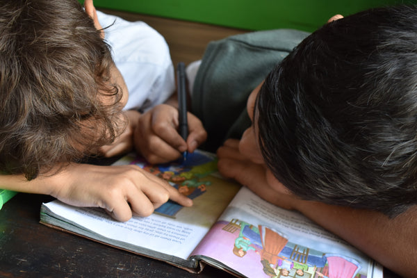 two boys with their heads down reading a book