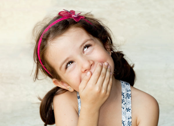 Little girl covering her mouth