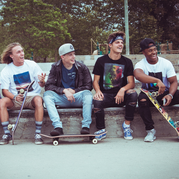 Group of Guys Sitting Around with Skateboards Smiling 