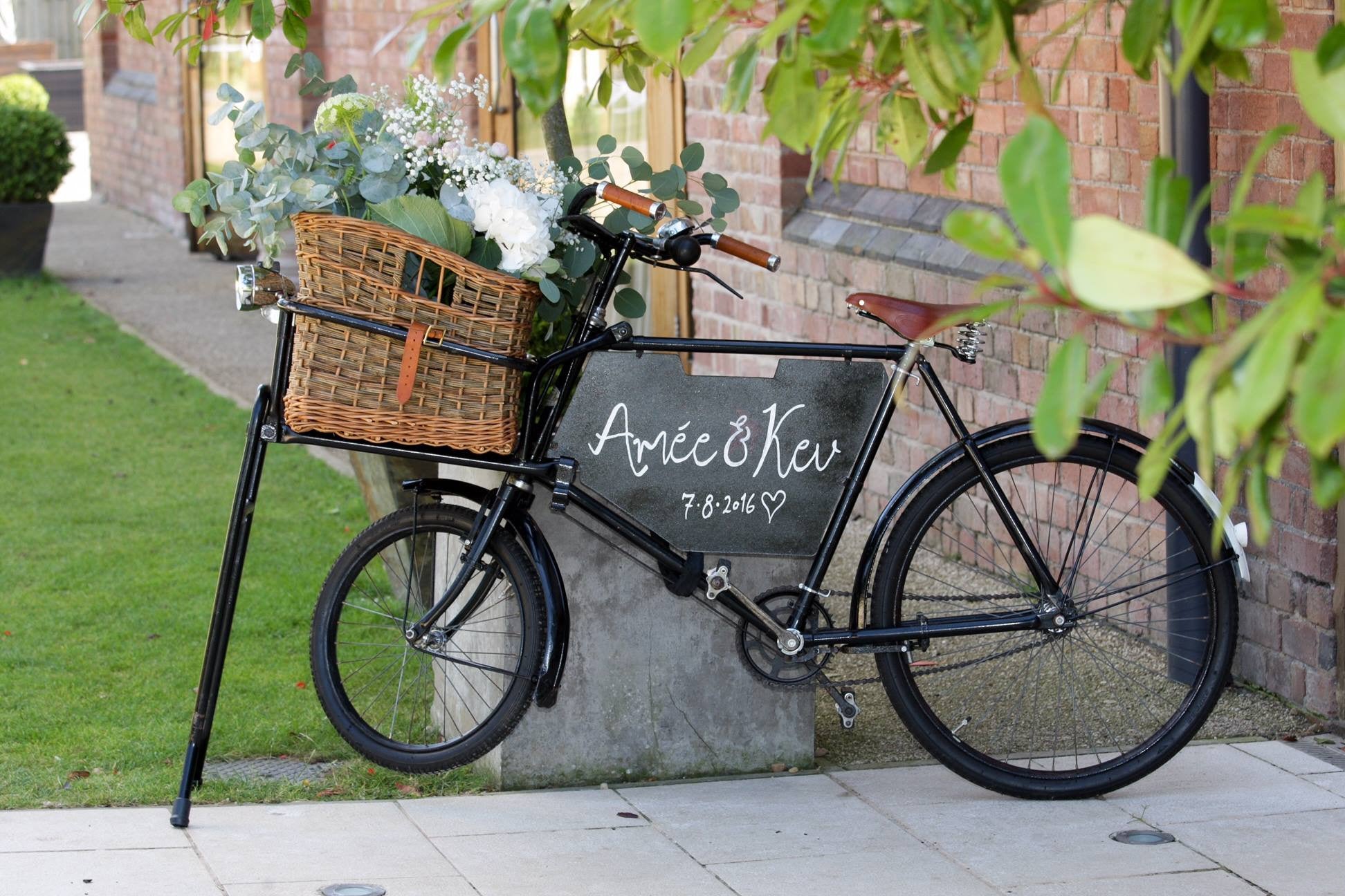 Vintage bike with wedding floral arrangement in shades of pink and cream in basket.