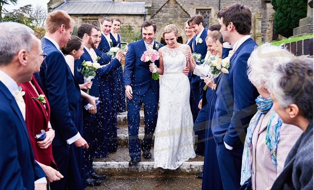 Wedding couple with confetti, holding pink Rose bouquet.