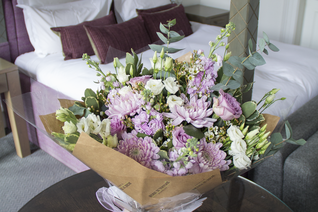 Beautiful corporate flower supply from Rose N Thyme for Blythswood Square Hotel Glasgow. The bouquet is on a table in front of a four poster bed 