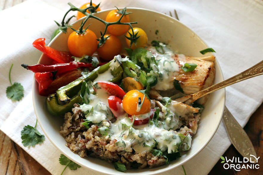 quinoa bowl with dressing, sliced peppers, and yellow tomatoes