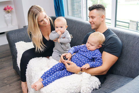 Family of four sitting on the couch, playing, smiling, having a wonderful time. Two young boys, mother, and father 