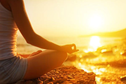 woman meditating on beach at sunrise