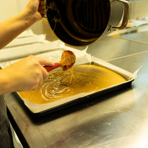 Scottish Tablet Mixture Poured Being Poured Out Into a Baking Tray With Parchment Paper. 