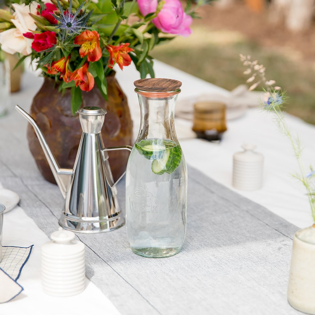 table with a vase of flowers and a glass bottle of water