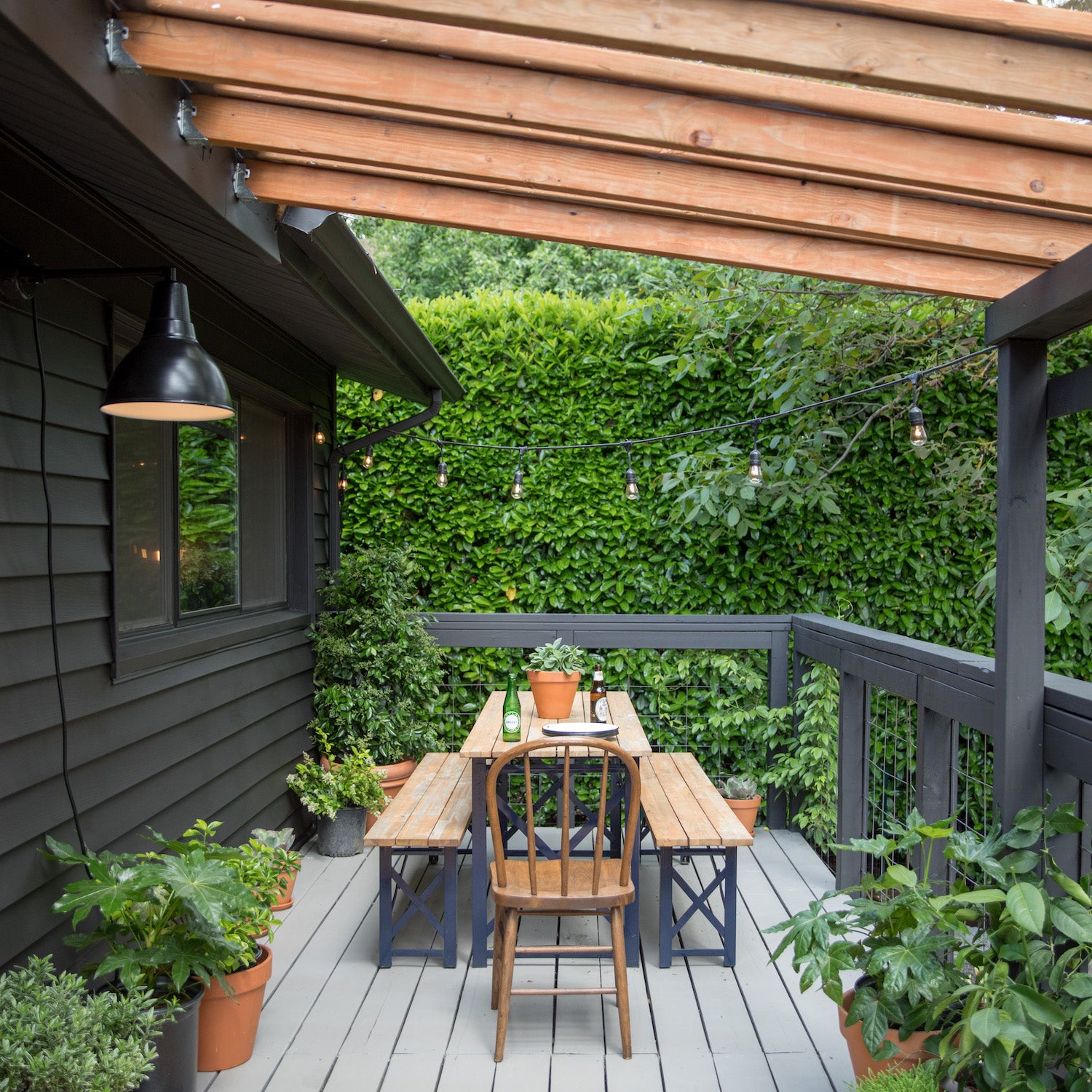 deck with a table and chairs surrounded by greenery