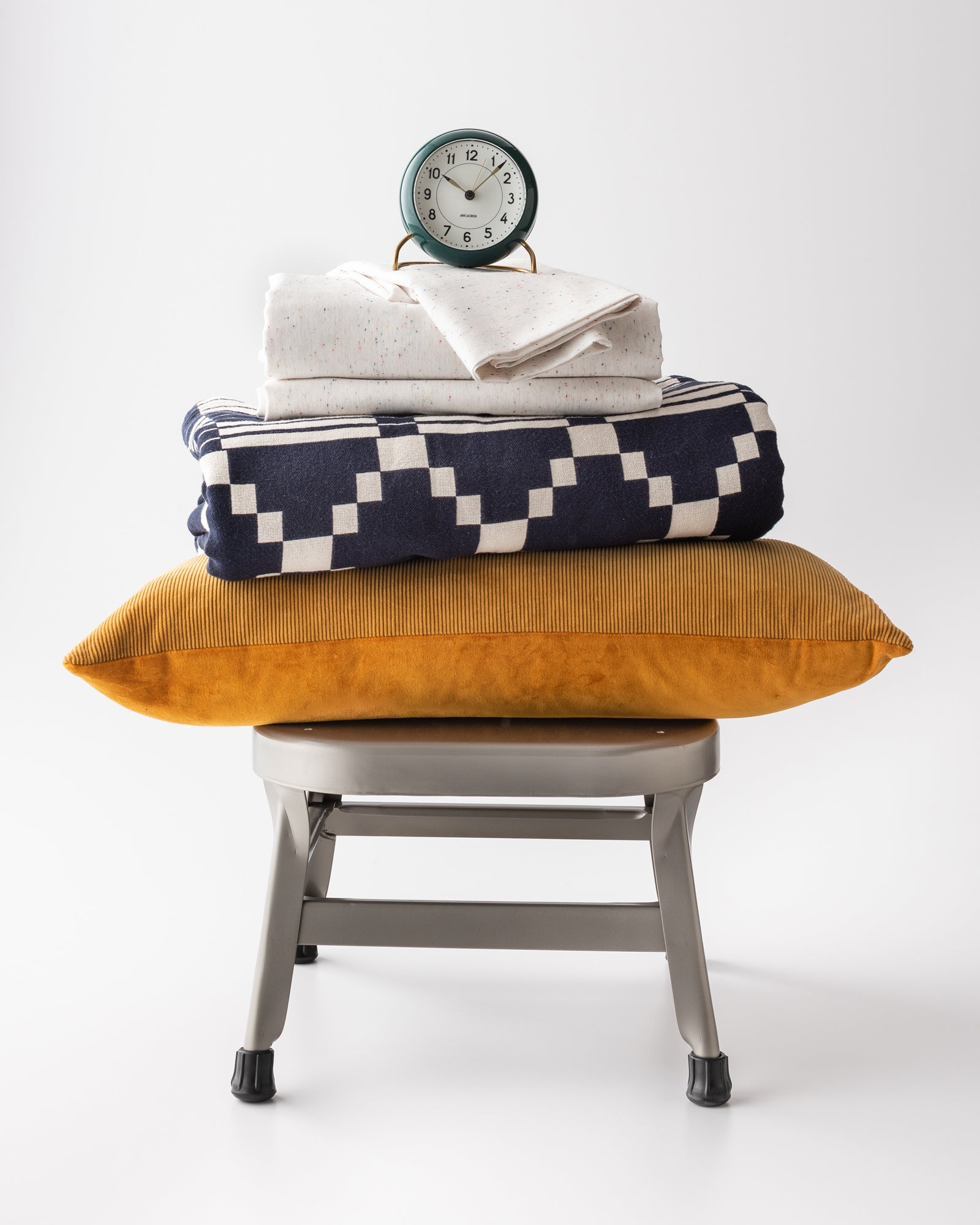 chair with a clock on top on a stack of pillows and blankets