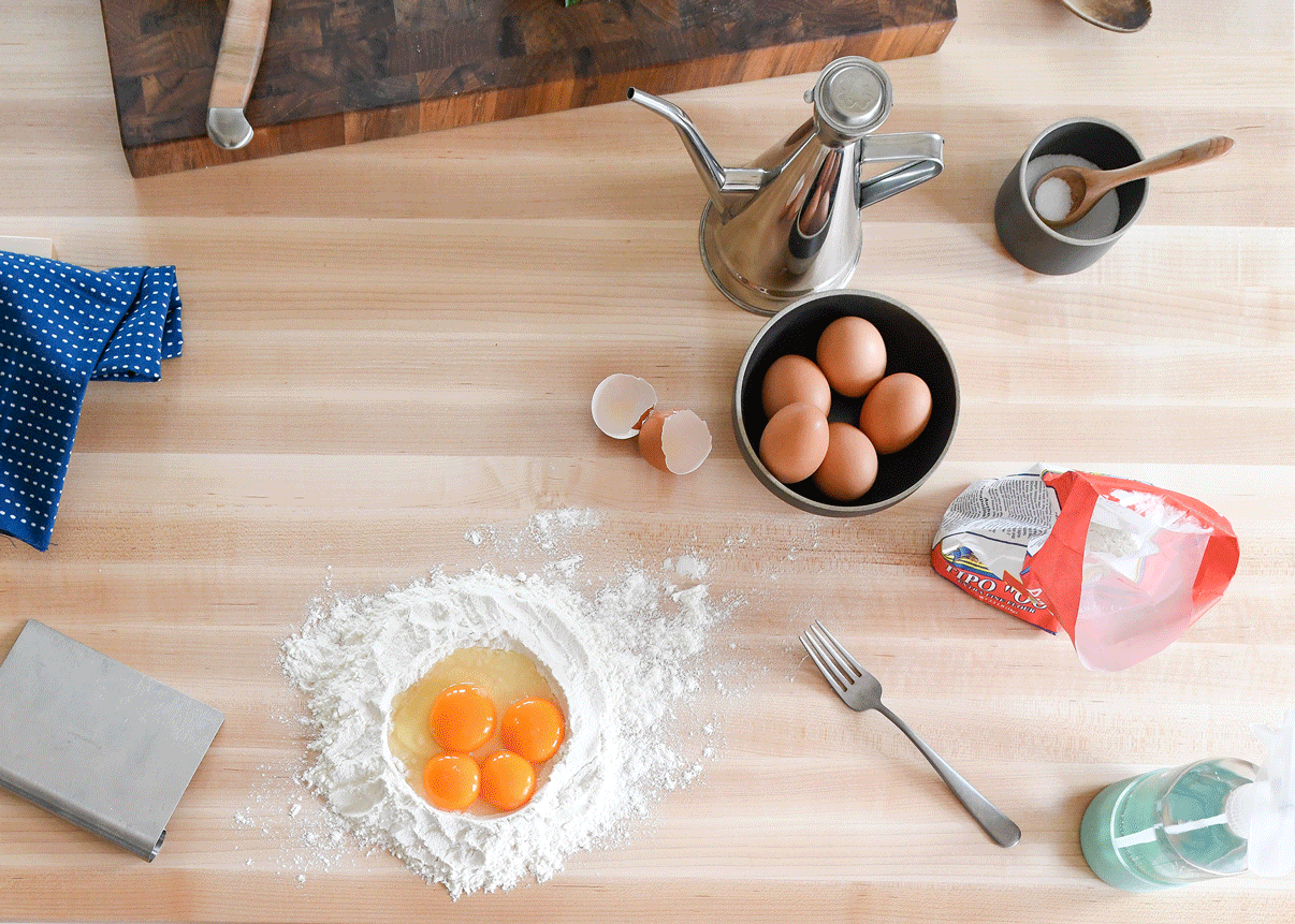egg yolks and egg white in pile of flour on a counter to make pasta