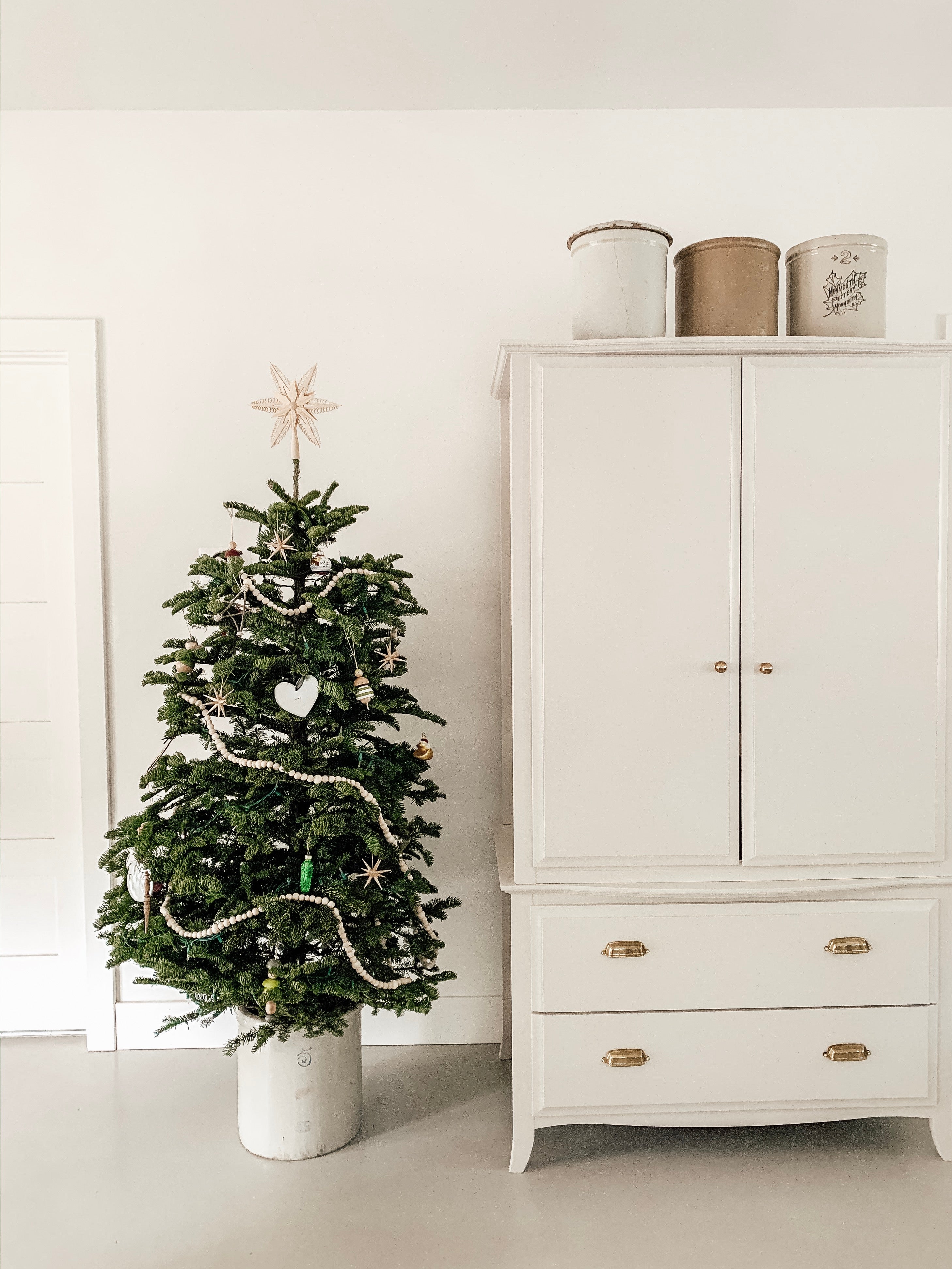 white cabinet next to a small christmas tree