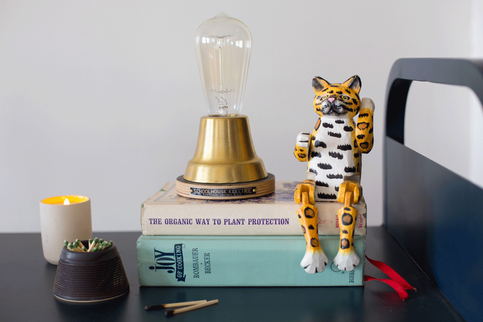 stack of books with a feline figurine on top and a lamp
