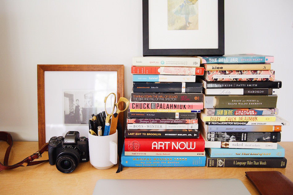 stack of books and a camera on a desk