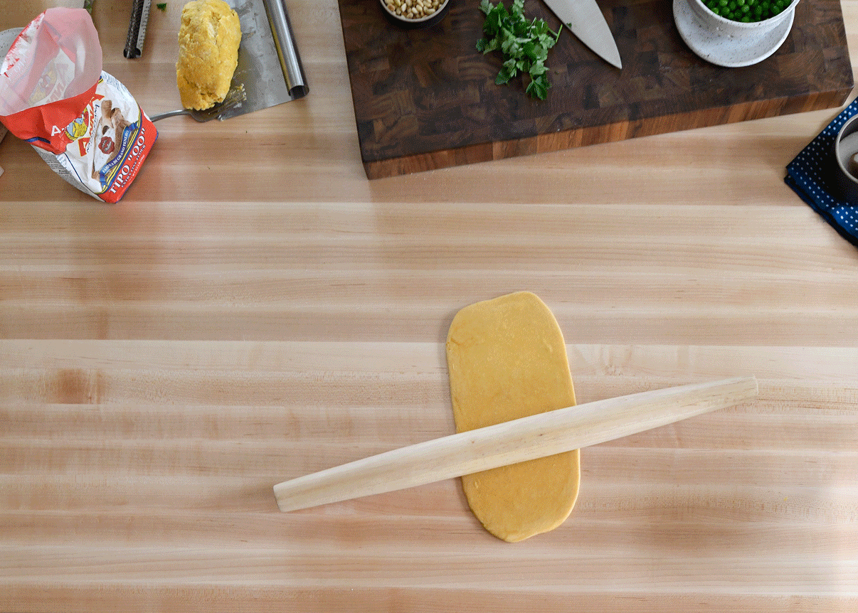 rolling pin on pasta dough on wooden counter