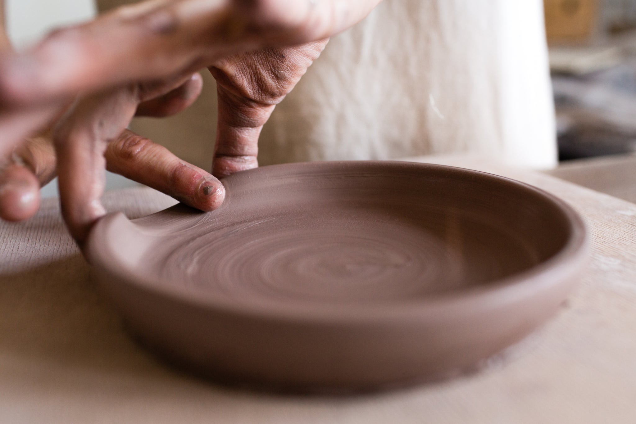 person making a dish out of clay throwing pottery