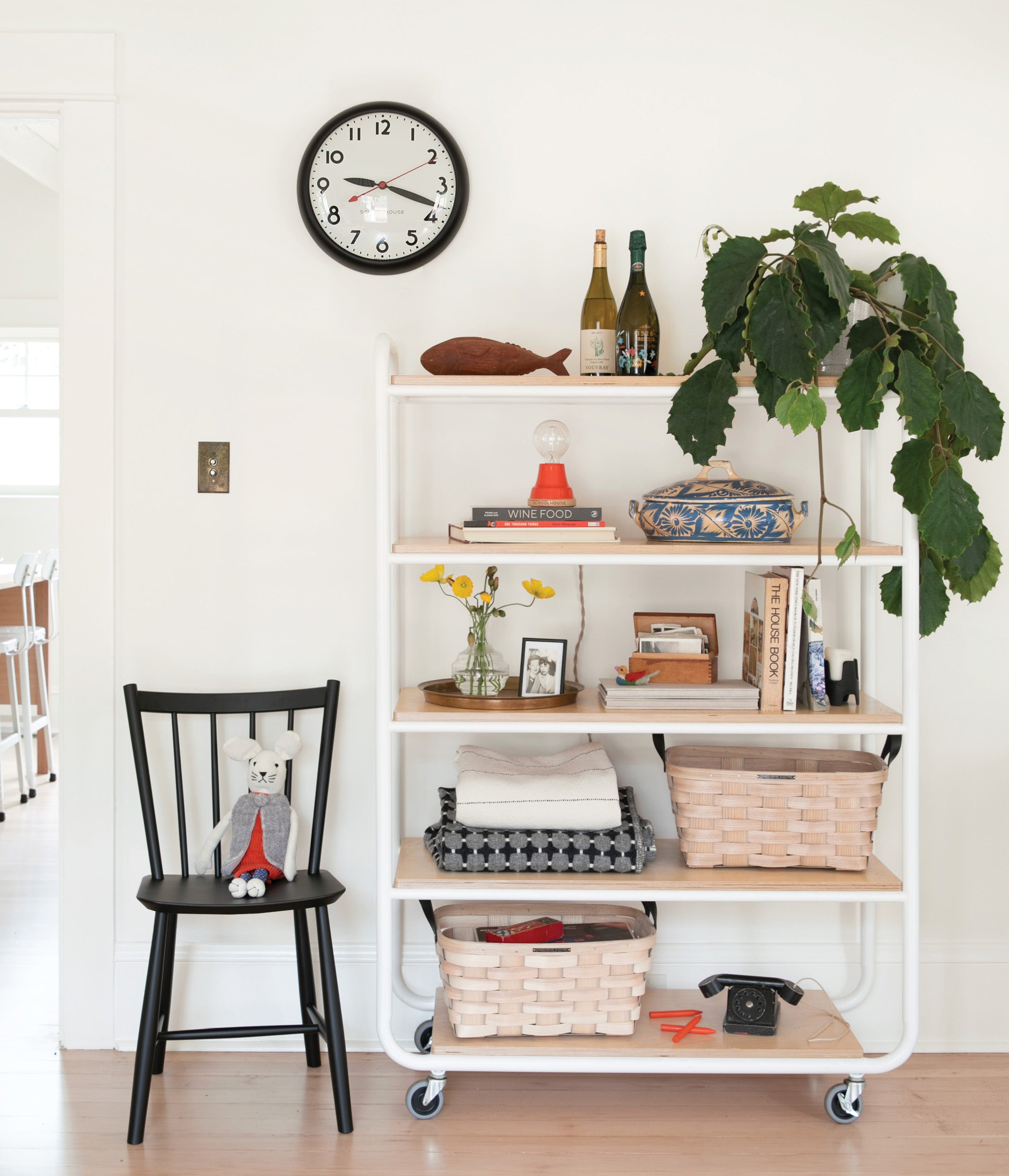 clock on a wall and a black chair and a shelving unit full of baskets and other items