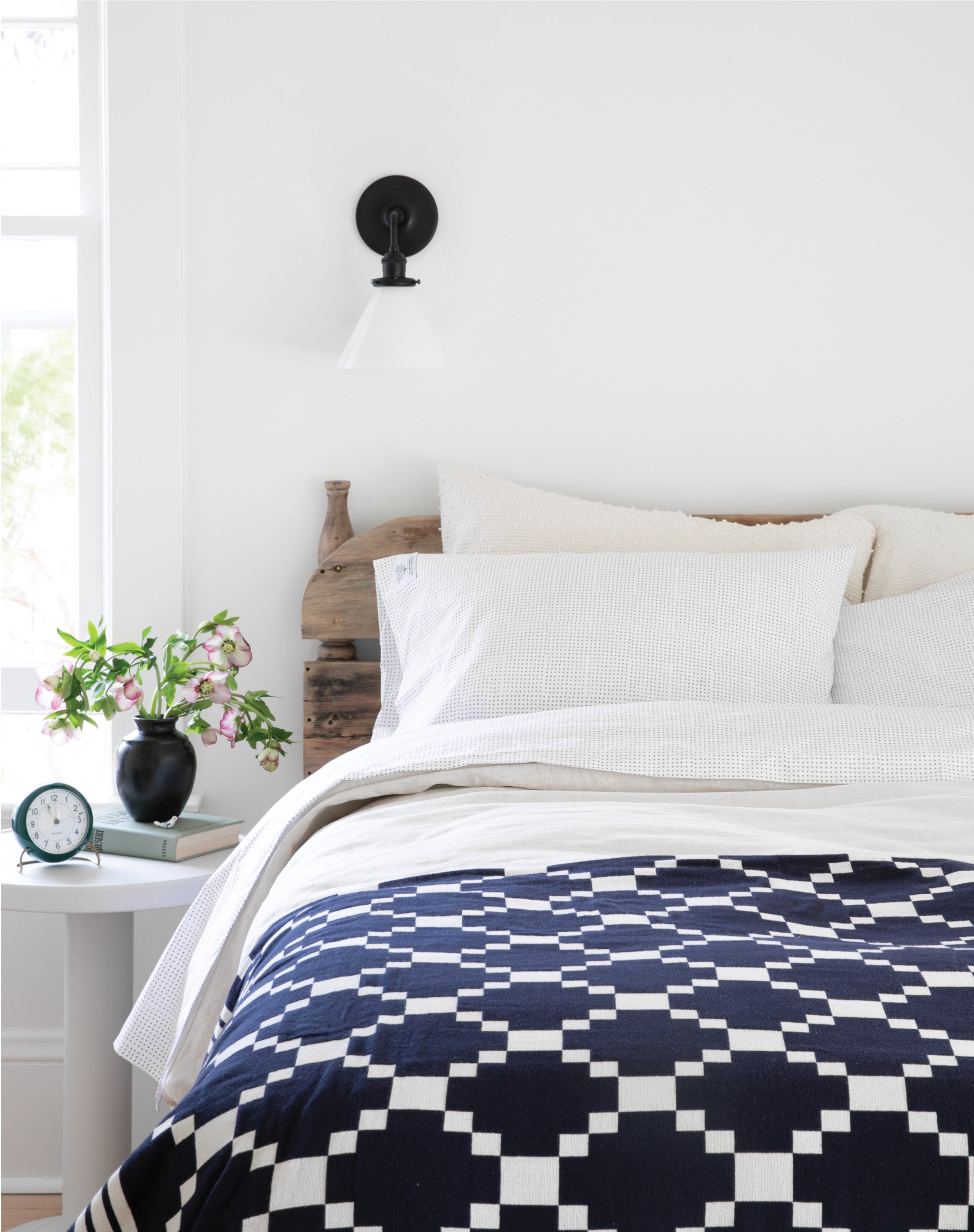 bed with a black and white checkered blanket and a black sconce